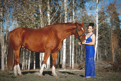 Woman standing by horse at forest