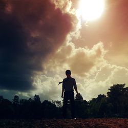 Man with arms raised against sky during sunset