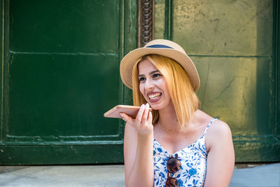 Portrait of smiling young woman against wall