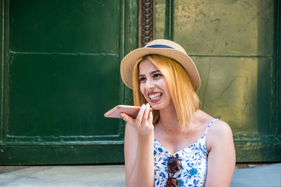 Smiling young woman wearing hat talking on phone outdoors