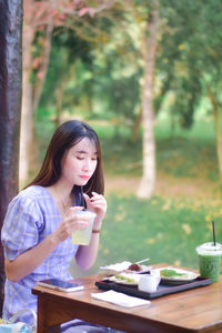 Young woman using mobile phone while sitting at park