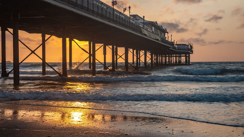 Pier over sea against sky during sunset