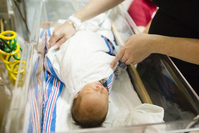 Mother swaddles newborn baby girl in hospital room with blanket