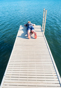 High angle view of people sitting on pier over sea