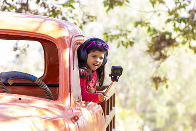 Portrait of smiling girl holding smart phone outdoors