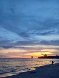 Silhouette person on beach against sky during sunset