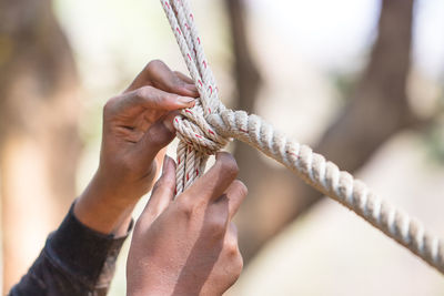 Close-up of hand tying rope 