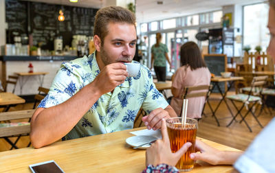 Portrait of young woman using mobile phone at restaurant