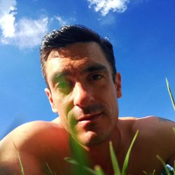 Low angle portrait of man against sky on sunny day