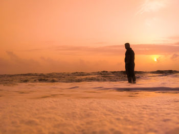 Silhouette man standing on beach during sunset