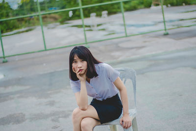 Portrait of young woman sitting on chair at basketball court