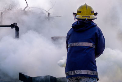 Rear view of firefighter spraying firefighting foam 