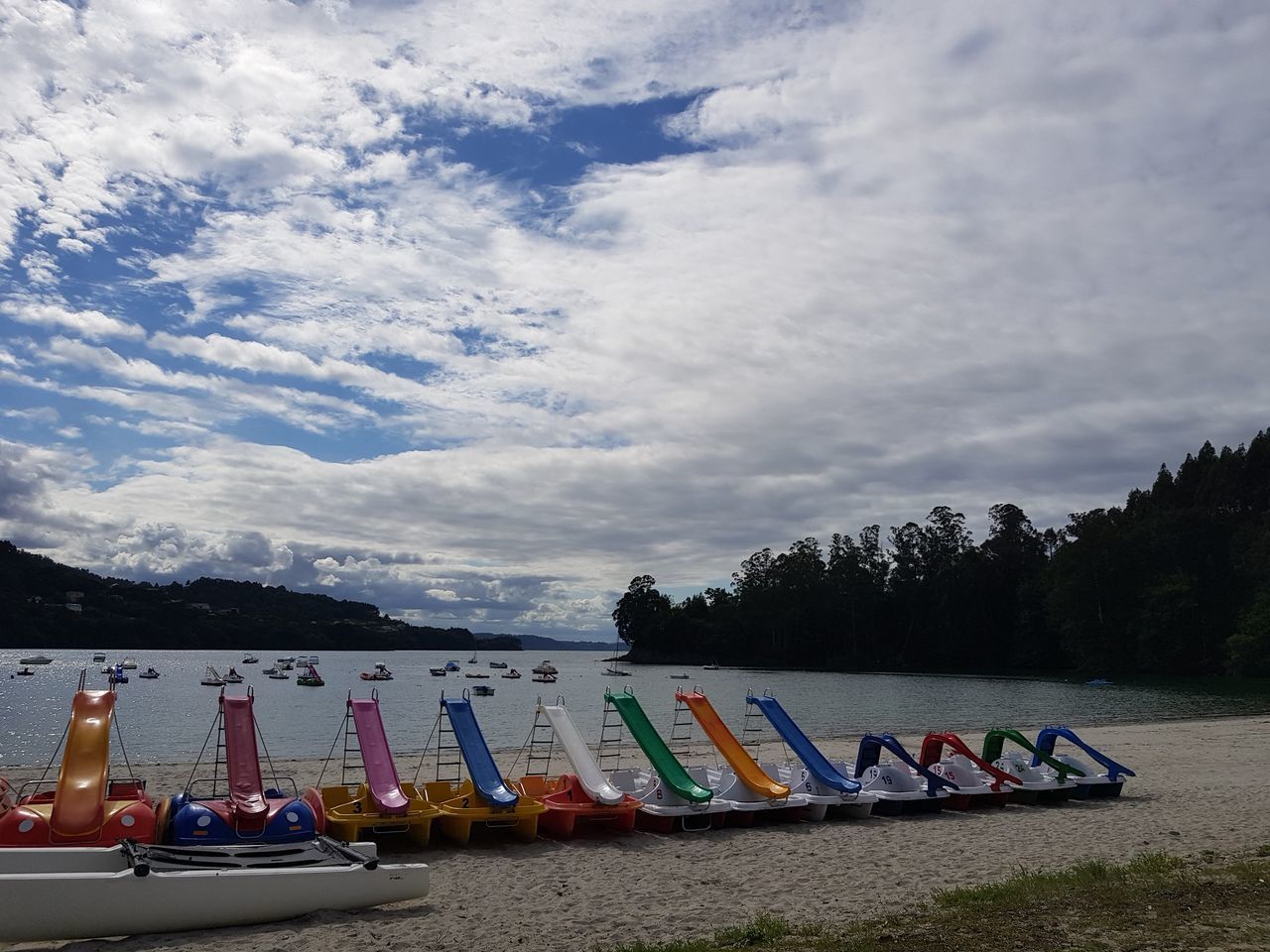 MULTI COLORED BOATS MOORED ON SHORE AGAINST SKY