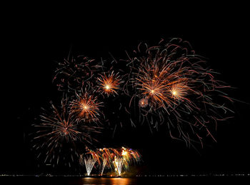 Firework exploding over sea against sky