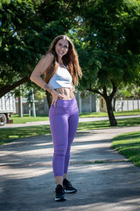 Portrait of young woman standing against trees