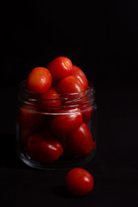 Close-up of tomatoes in glass jar against black background