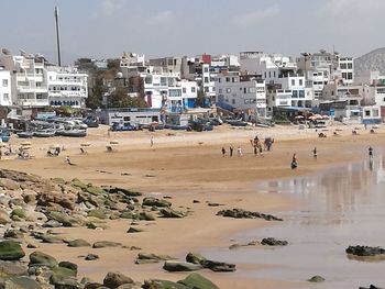 People at beach against sky in city