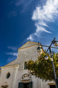 Low angle view of trees and building against blue sky