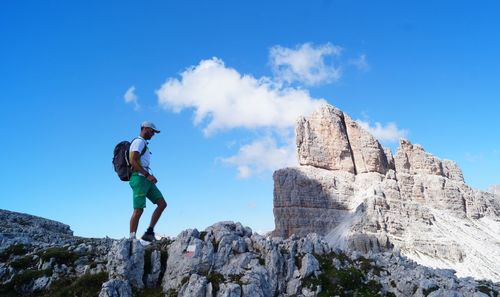 Low angle view of man standing on rock against sky