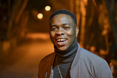 Portrait of laughing young man standing on road at night