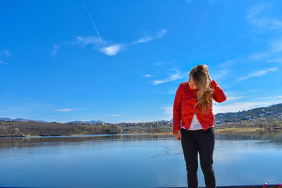 Woman standing by lake against sky