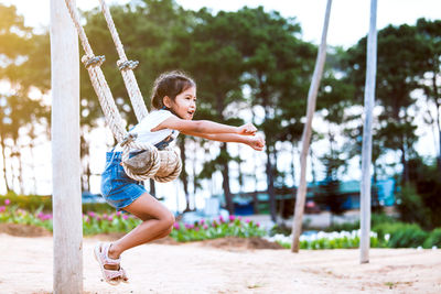 Full length side view of girl swinging at playground