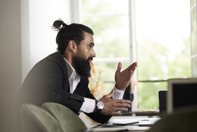 Side view of young man using digital tablet while sitting at home