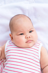 High angle view of cute baby lying on bed at home