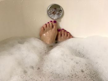 Low section of person in bathtub at home