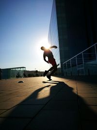 Silhouette men dancing on footpath against sky