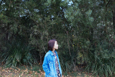 Mid adult woman standing amidst trees in forest