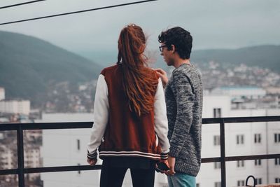 Rear view of friends standing against cityscape