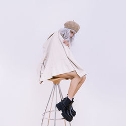 Side view of woman standing against white background