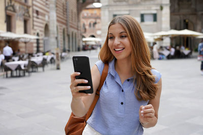 Young woman using smart phone on street