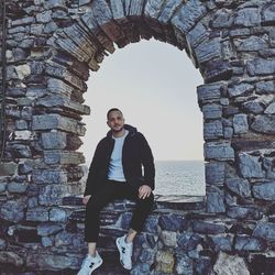 Portrait of young man standing against stone wall