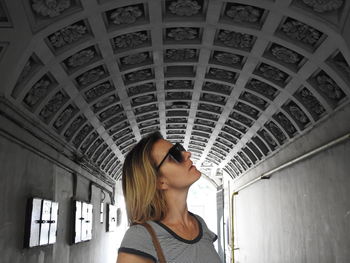 Woman wearing sunglasses while standing in tunnel