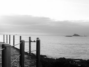 Pier on sea against cloudy sky