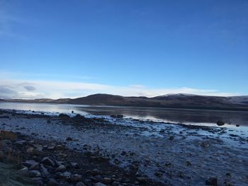 Scenic view of beach against blue sky