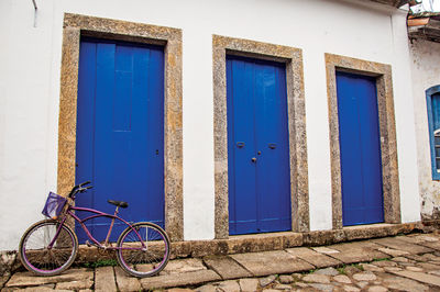 Bicycle in front of closed blue doors and stone sidewalk in paraty, brazil