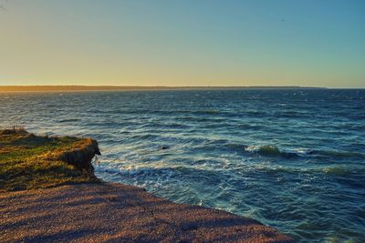 Scenic view of sea against clear sky at sunset