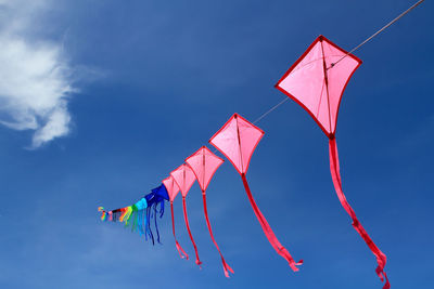 Low angle view of kites flying in blue sky