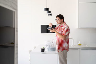 Side view of young man using mobile phone at home