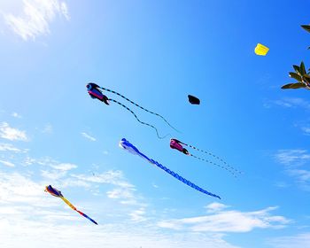 Low angle view of kites flying against blue sky