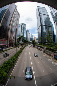 Vehicles on road amidst buildings against sky in city