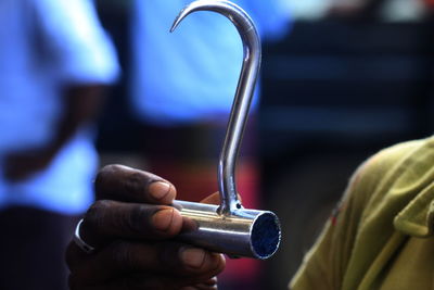 Close-up of man holding steel hook