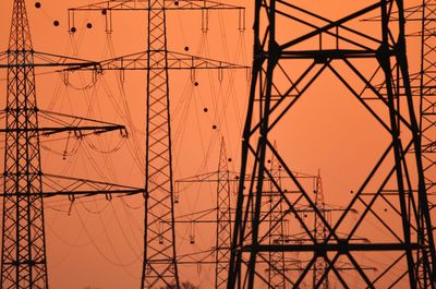 Low angle view of electricity pylon against sky during sunset