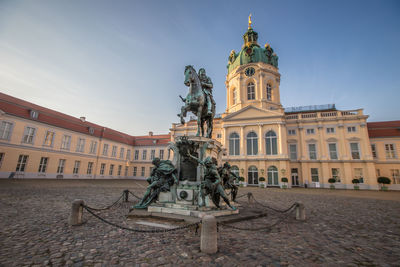 Statue in city against sky