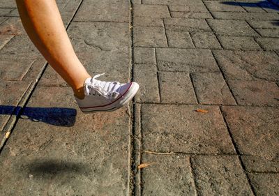 Low section of woman walking on footpath