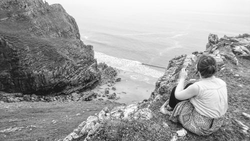 Woman looking at sea while sitting on cliff