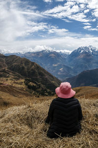 Rear view of woman looking at mountains against cloudy sky